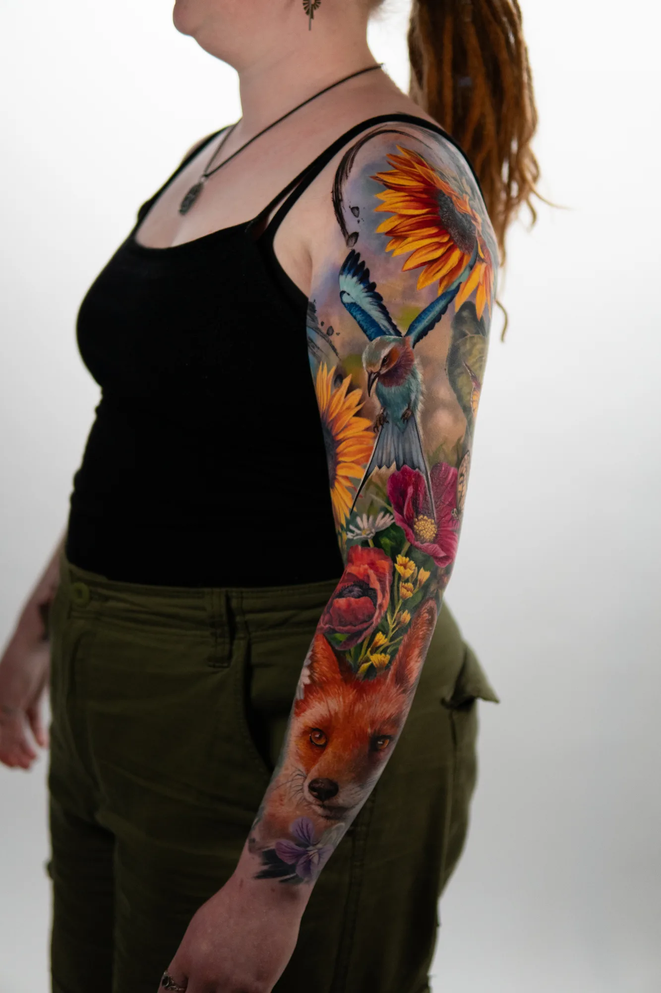 Colorful sleeve tattoo featuring a fox, flowers, and a bird.
