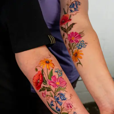 Colorful floral tattoo on two people's arms.