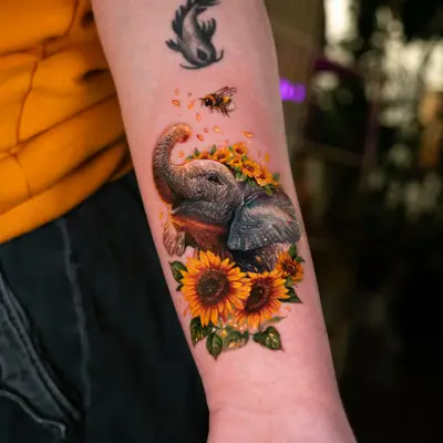 Tattoo of an elephant surrounded by sunflowers on forearm.