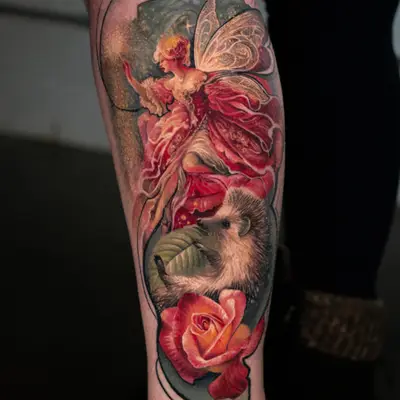 Tattoo of a fairy with wings, flowers, and a hedgehog on a leg.