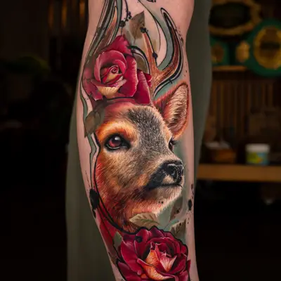 Tattoo of deer head with roses and abstract elements on leg.