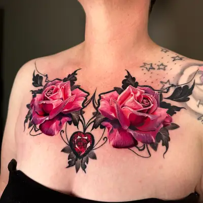 Tattoo of two pink roses with black leaves and a jeweled heart on the chest.
