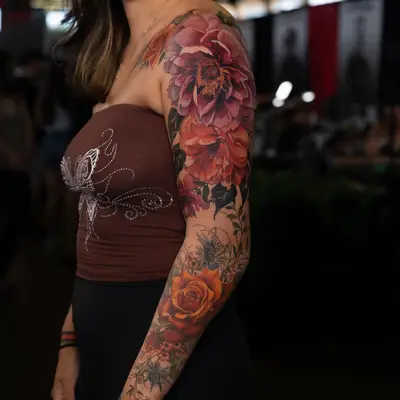 A vibrant floral tattoo covering a woman's arm with bold colors and intricate details.