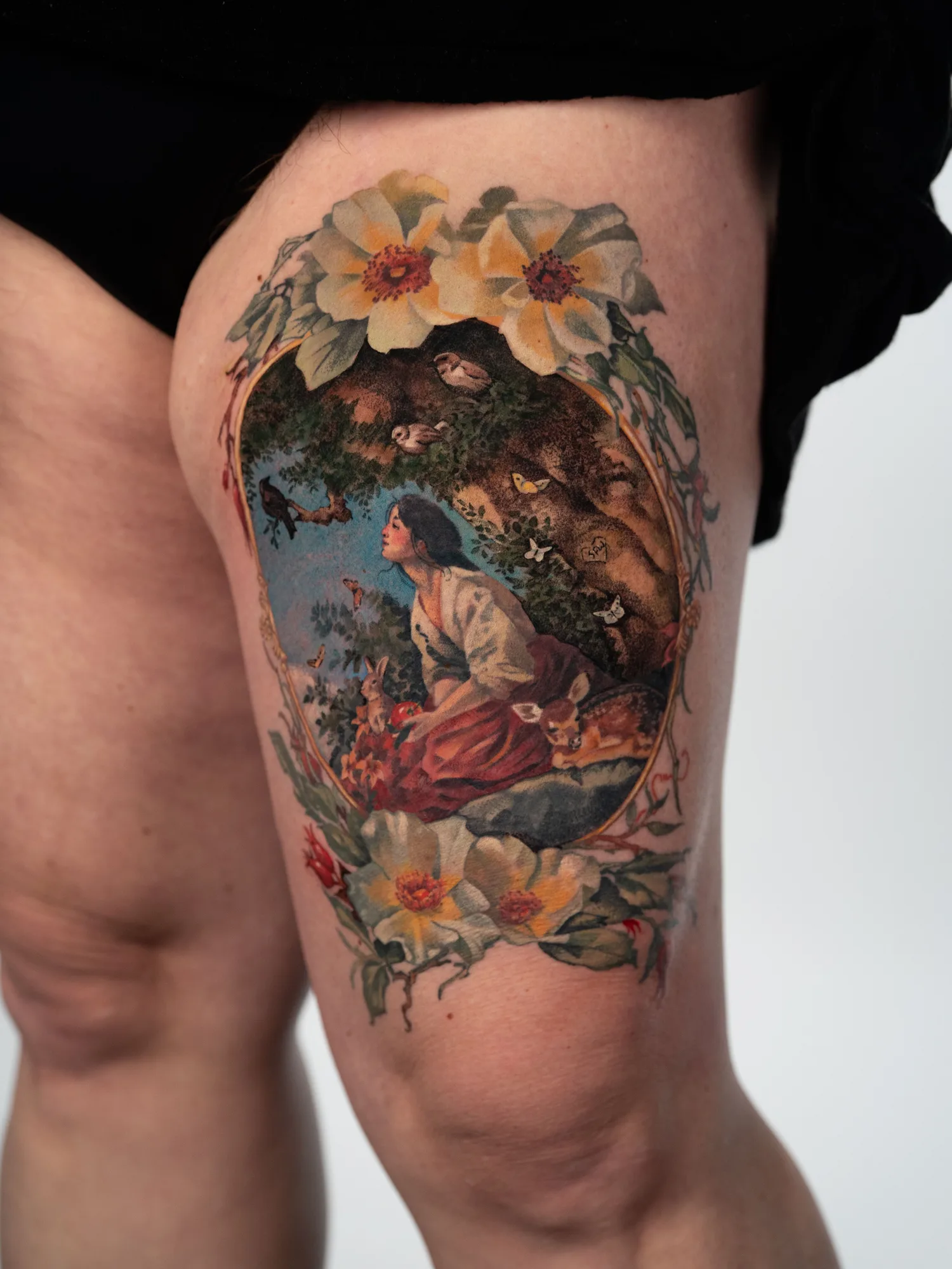 Painterly tattoo of a dreamy lady surrounded by forest animals and framed by flowers.