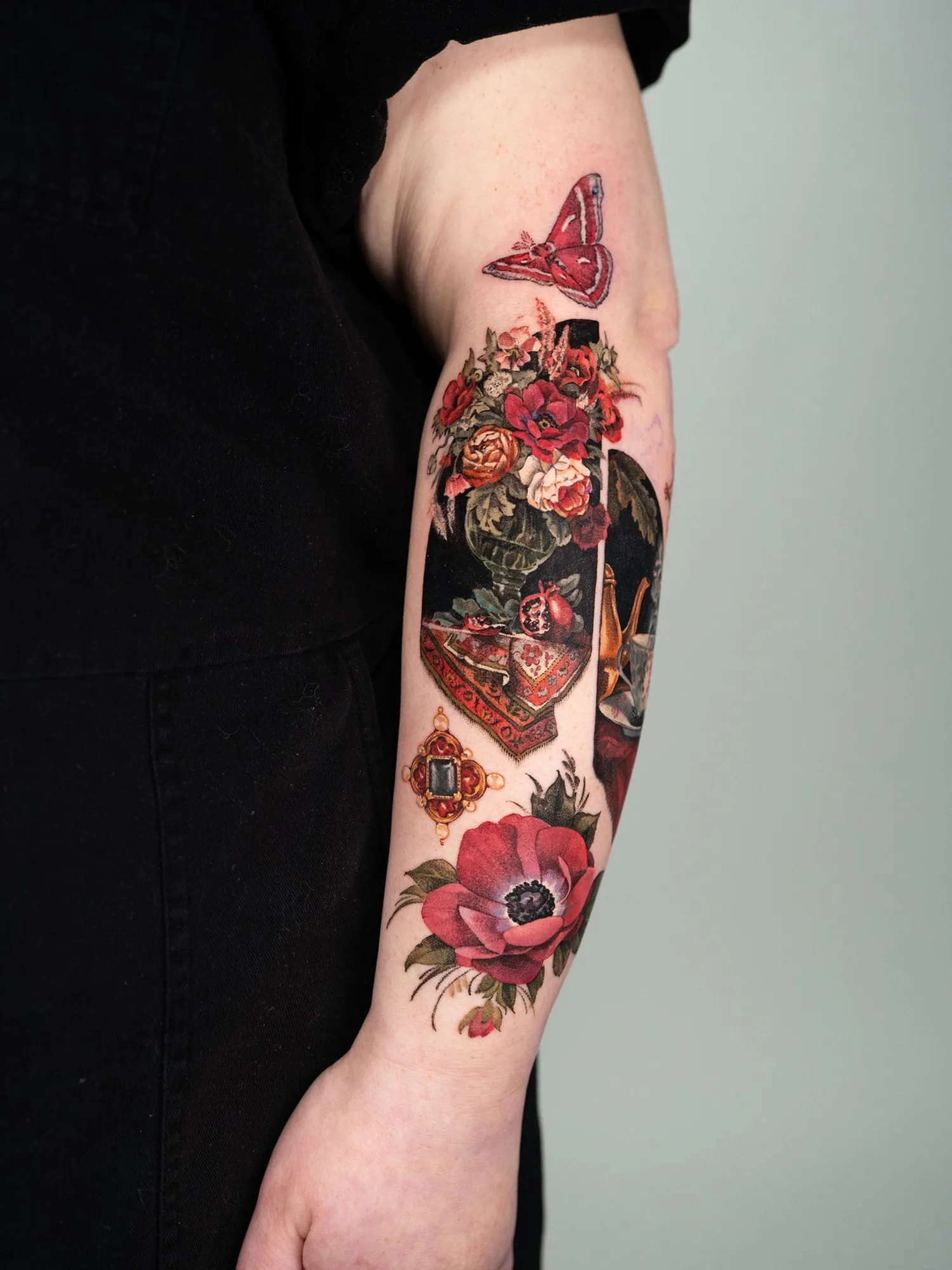 Large tattoo featuring smaller microrealism designs including a Dutch still life, gemstones, flowers, and a butterfly.