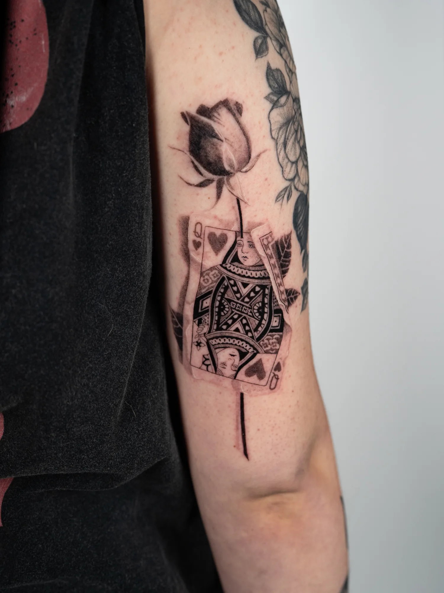 Micorealism tattoo of a crumpled Queen of Hearts with a rose going through it.