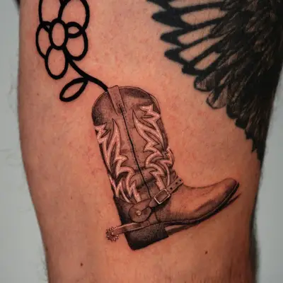 Tattoo of a micorealism cowboy boot with an illustrative stem coming out of the top.