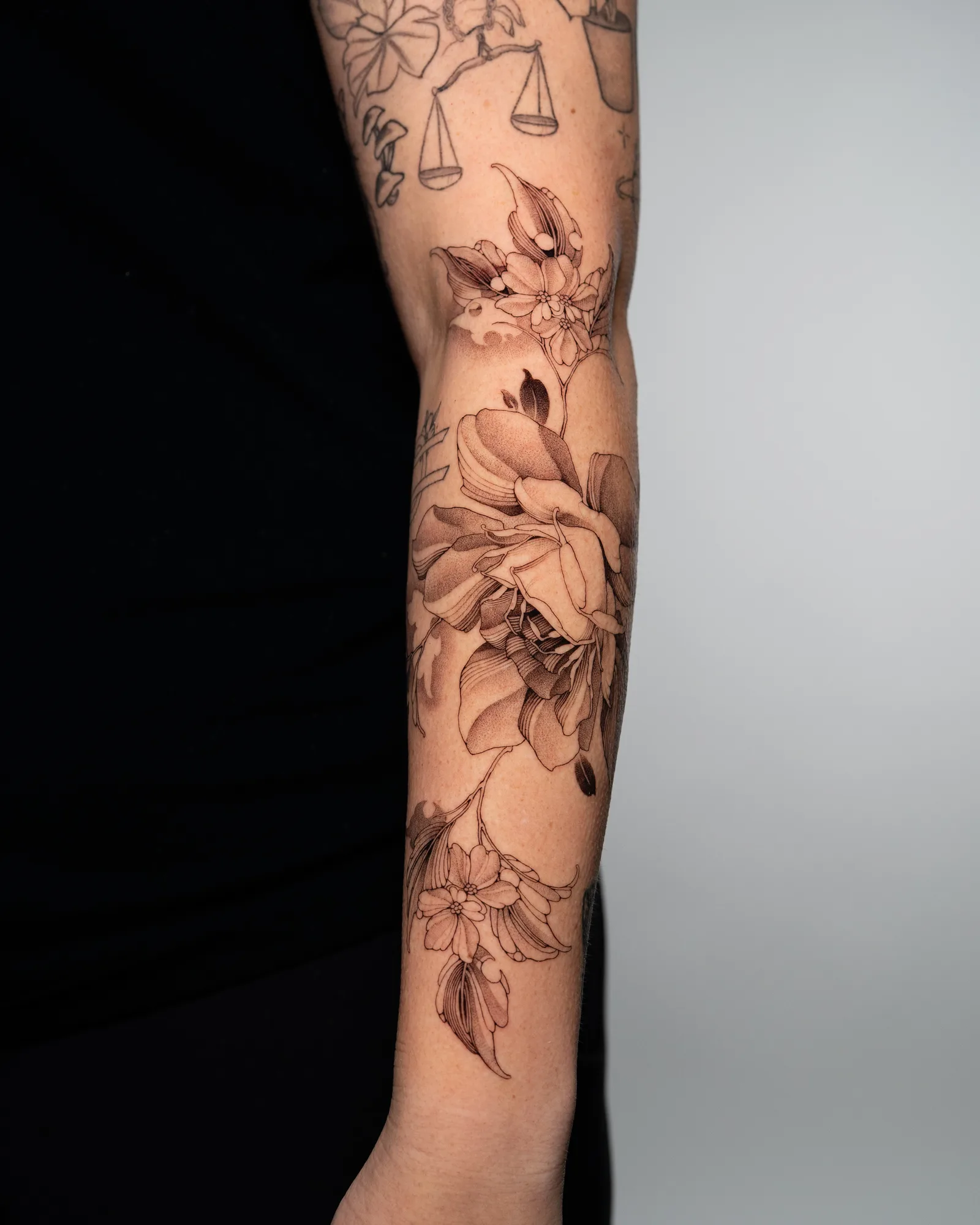 A floral tattoo on the outer forearm, showcasing fine line roses and leaves.