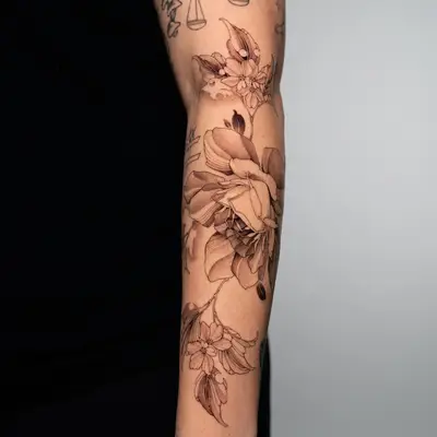 A floral tattoo on the inner forearm, showcasing detailed roses and leaves.