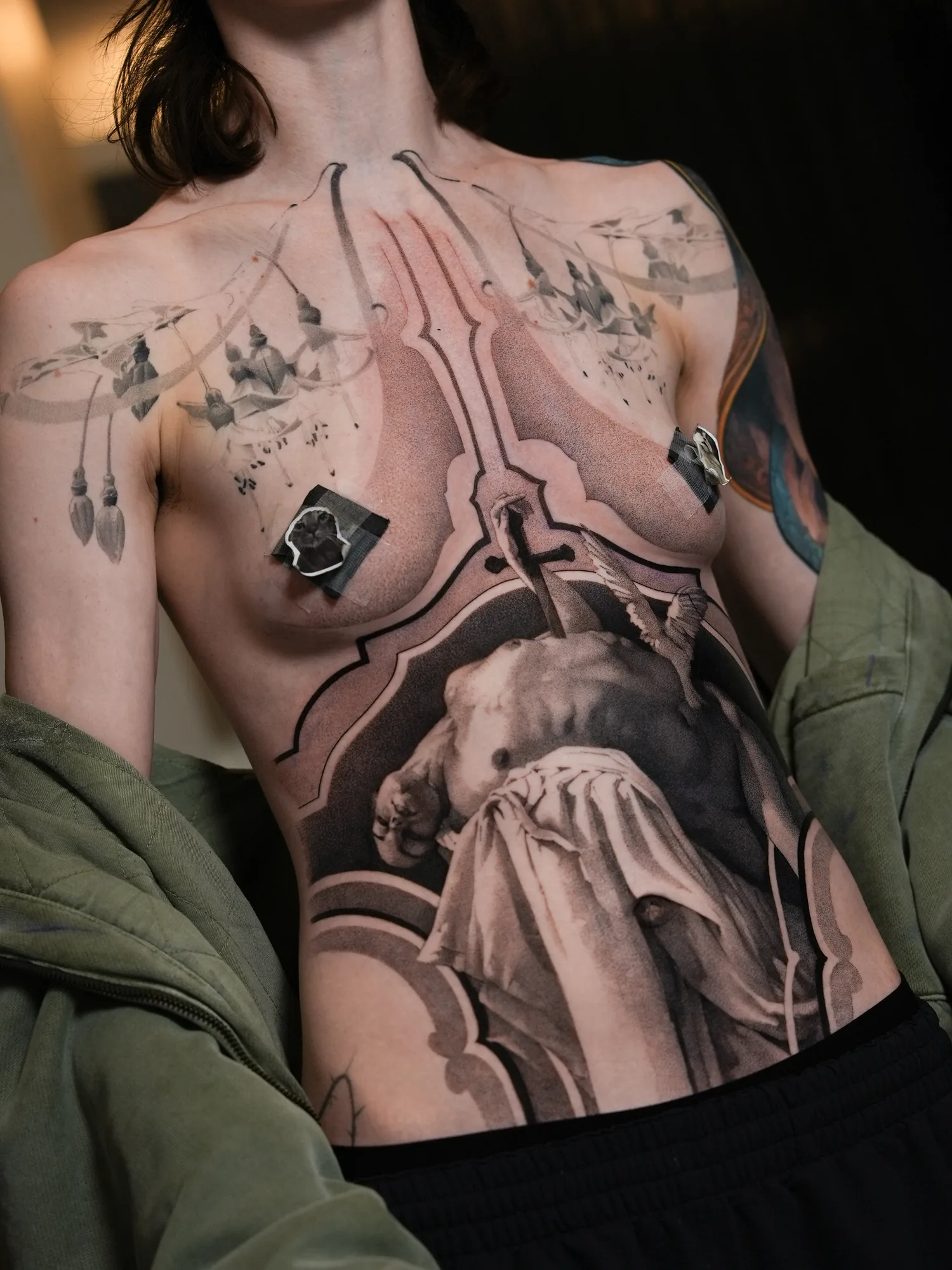 Full front panel tattoo of a figure with ornamental blackwork in a realism style.