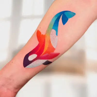 Colorful tattoo of a whale design in vibrant hues on the forearm.