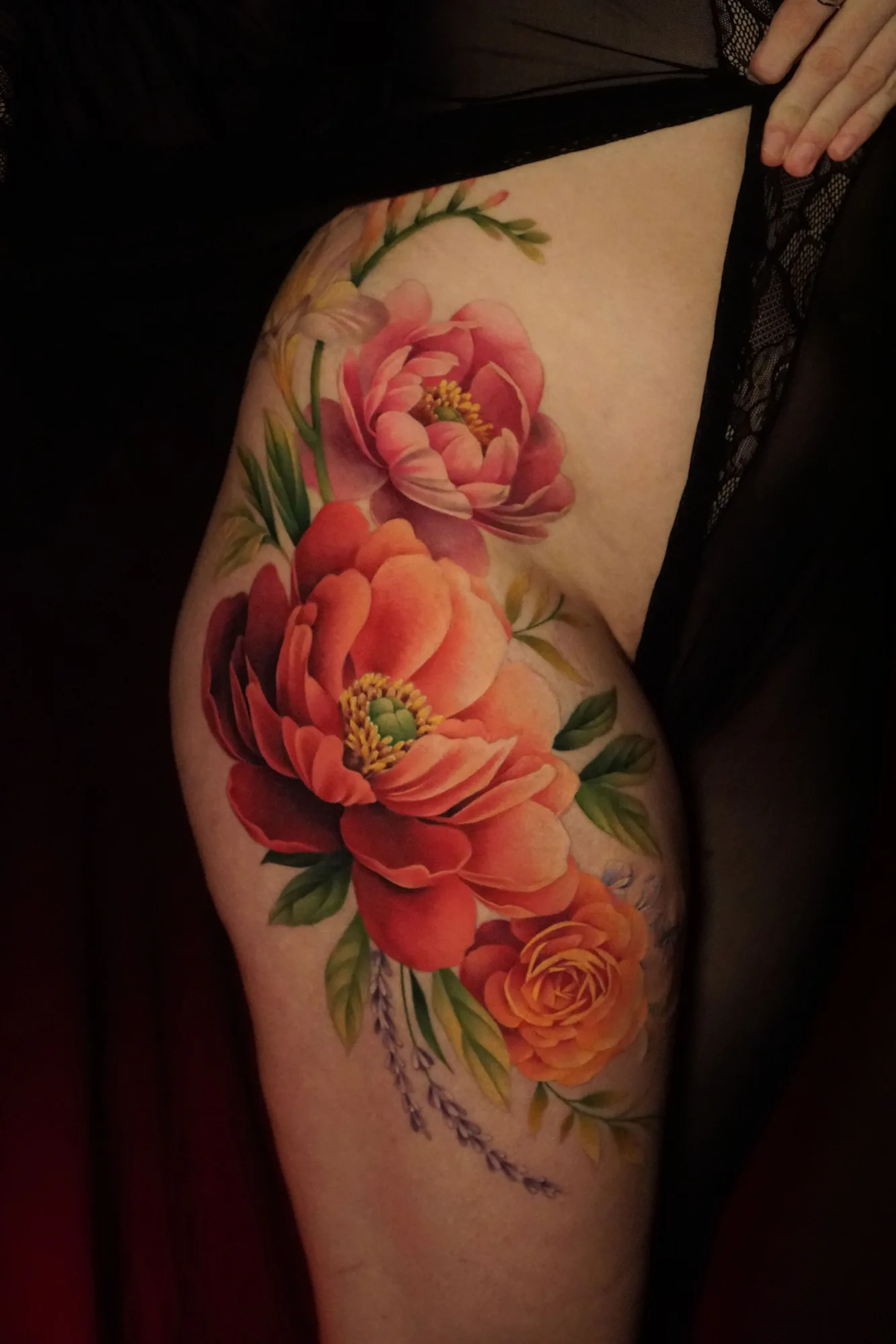 A vibrant tattoo featuring colorful peonies and flowers on the hip.