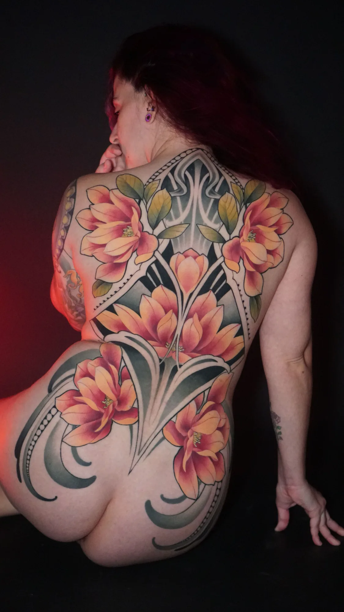 A vibrant floral and ornamental tattoo covering the entire back with bold colors and patterns.