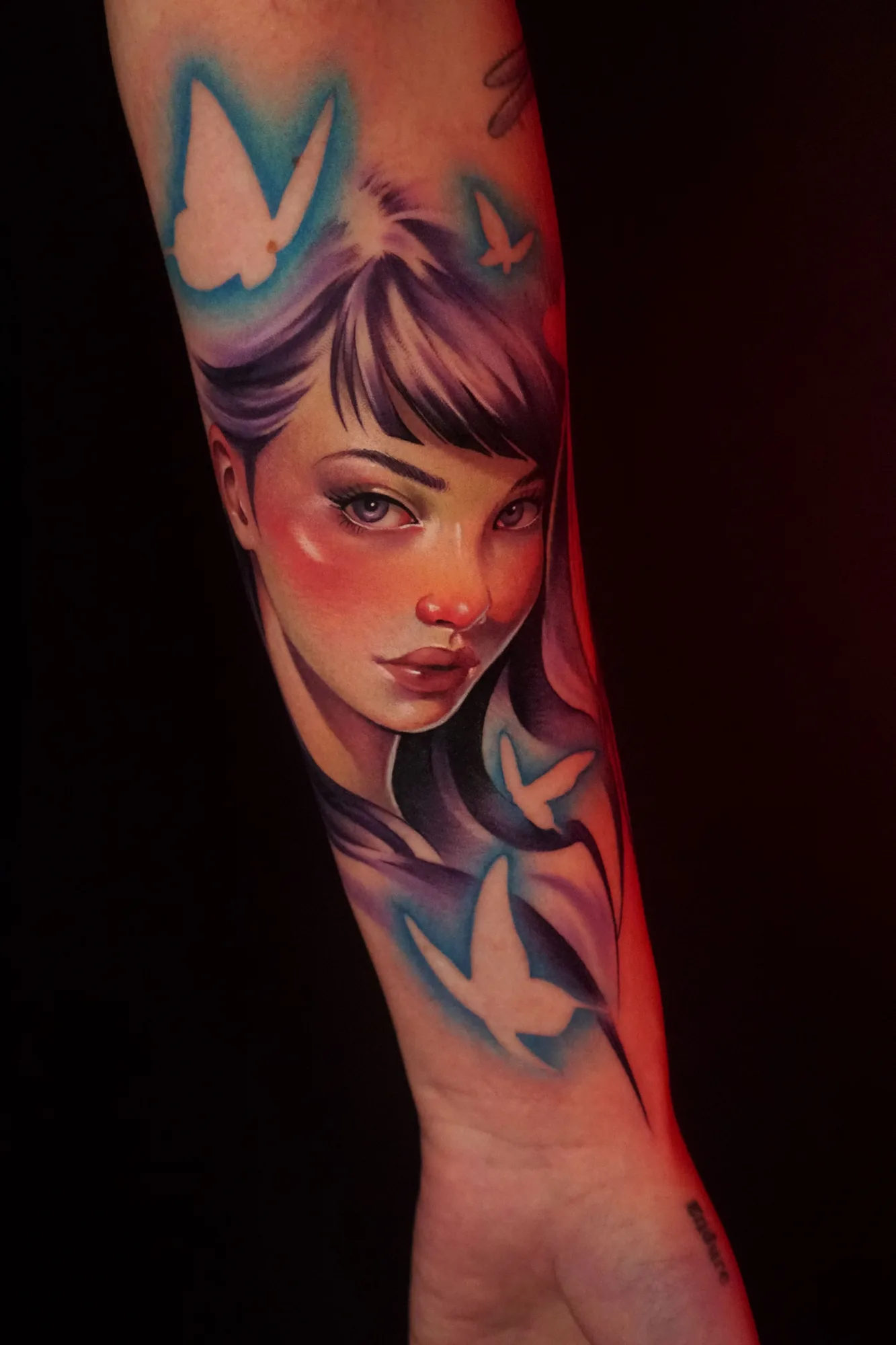 Portrait of a woman with butterflies in vibrant colors on forearm.