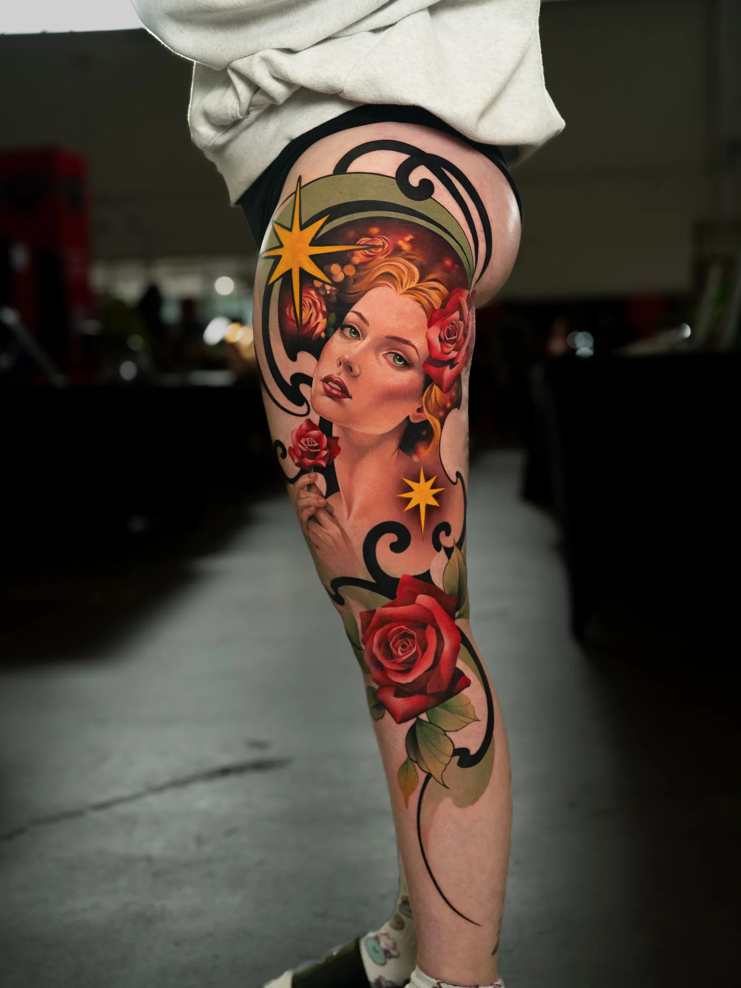 A vibrant, detailed tattoo of a woman with roses on a leg in a neotraditional style.