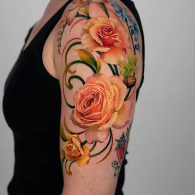 Colorful floral tattoo featuring roses and leaves on a woman's arm.