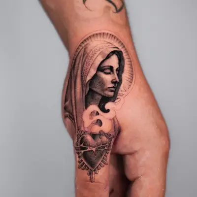Tattoo of a religious figure and sacred heart on a hand.