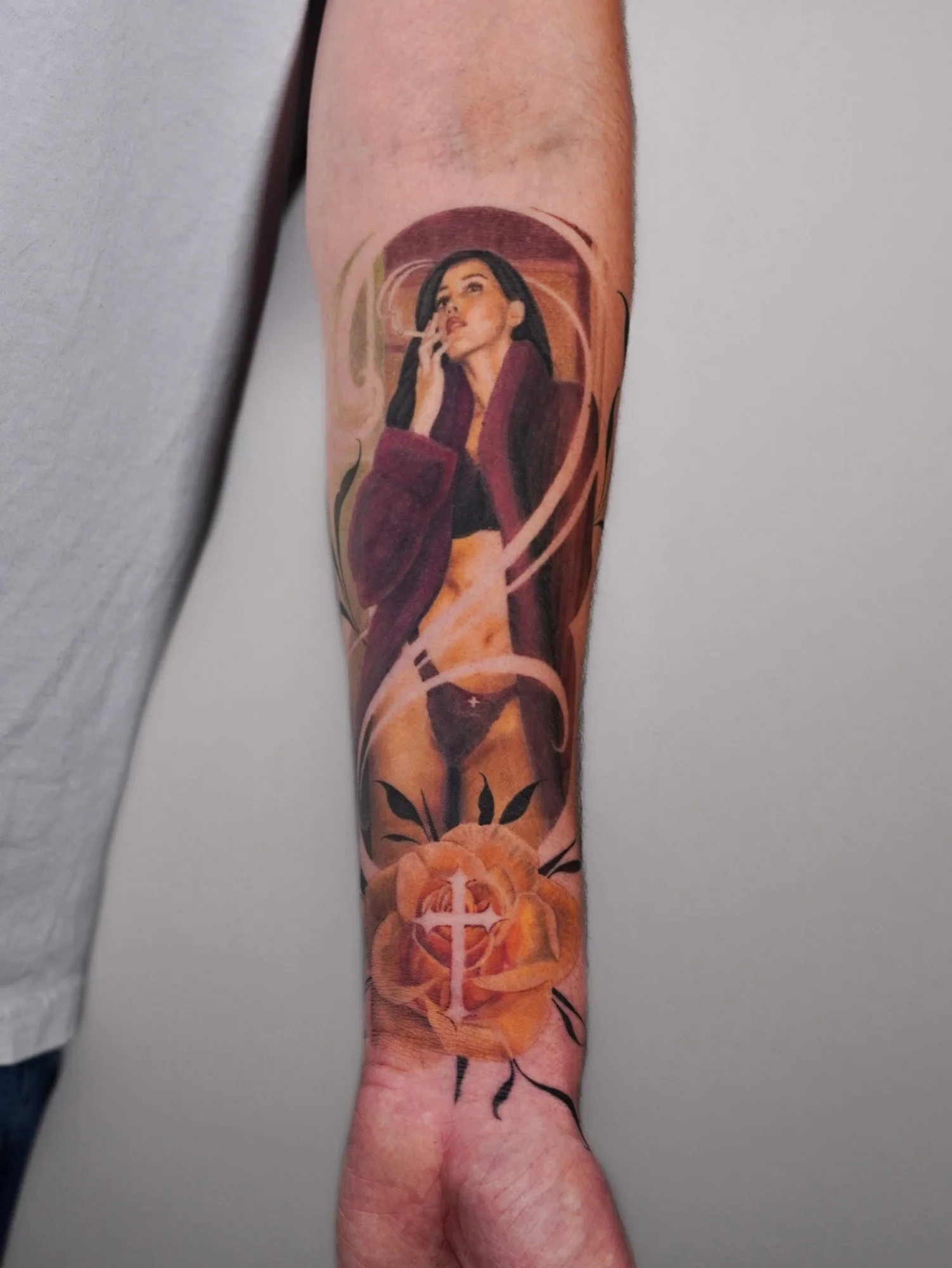 Realism tattoo of a woman and rose on forearm