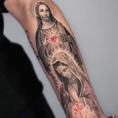 Tattoo of Jesus and Mary on forearm with red Sacred Heart detail.