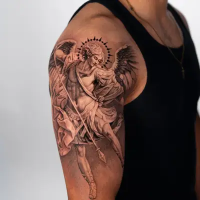 Tattoo of angel with wings and spear on man's upper arm