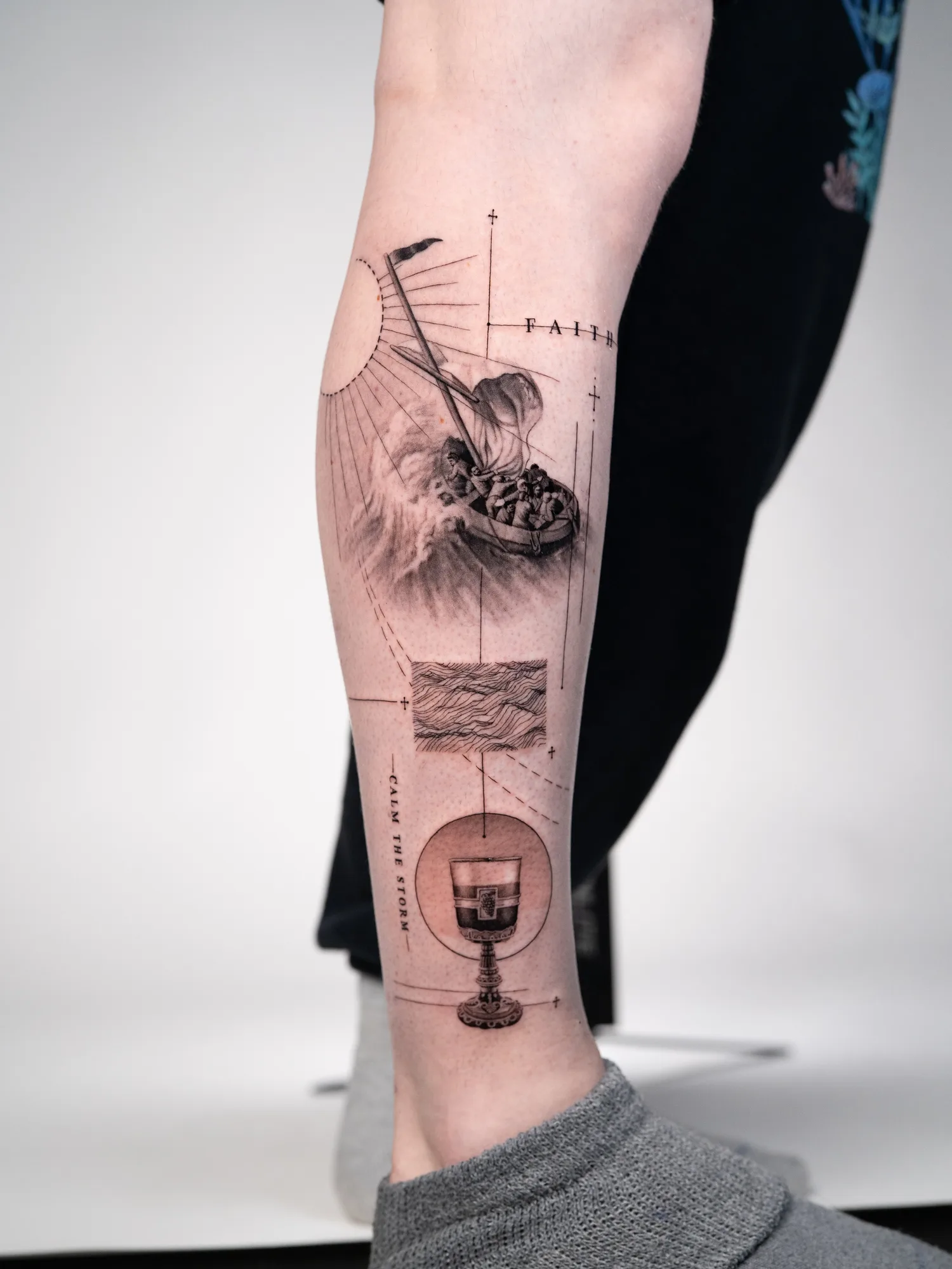 Tattoo of boat with passengers, compass, and chalice on forearm