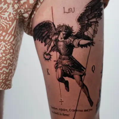 Tattoo of an angelic figure wielding weapons and surrounded by text on the thigh.