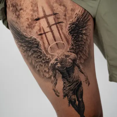 A detailed black and grey tattoo of an angel bathed in flames on a thigh.