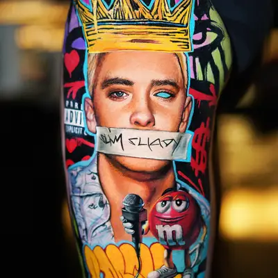 Colorful tattoo of a crowned figure with branded elements