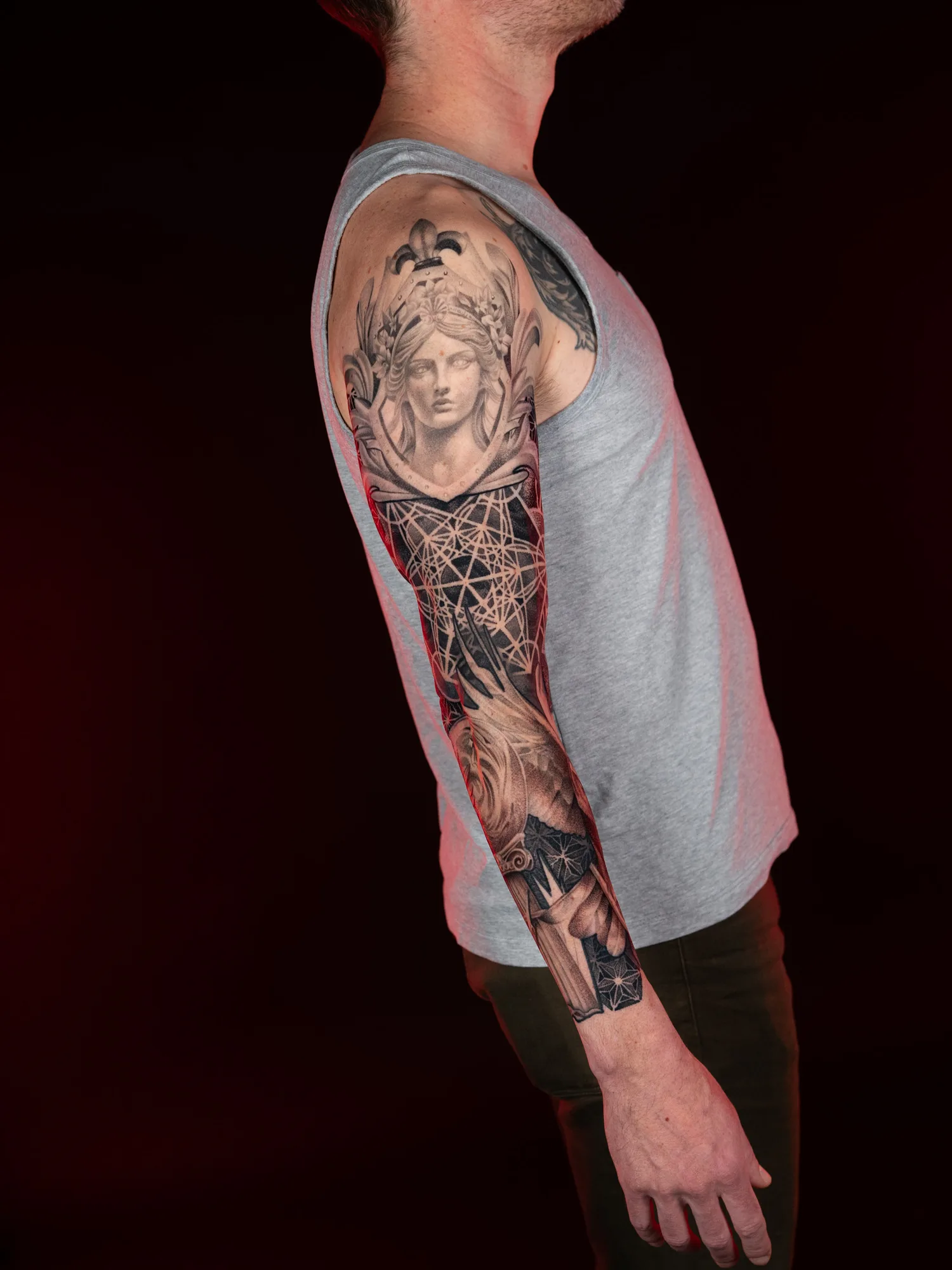 Black and grey sleeve tattoo with a classical bust and geometric design.