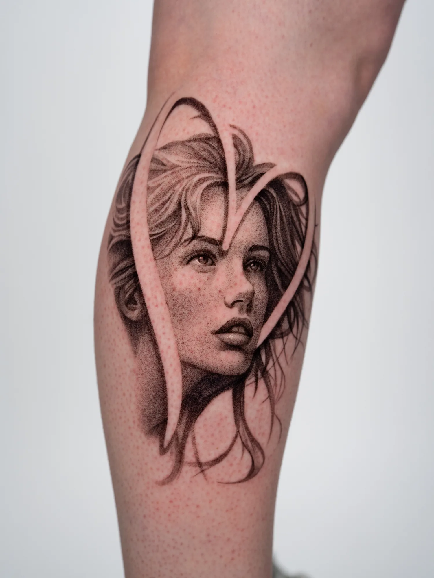 Realistic portrait tattoo with heart-shaped negative space.