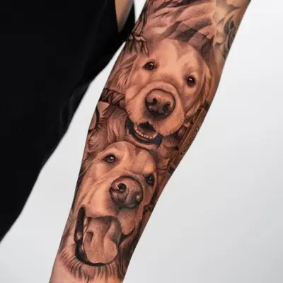 Realistic portrait tattoo of two golden retrievers on an inner forearm.