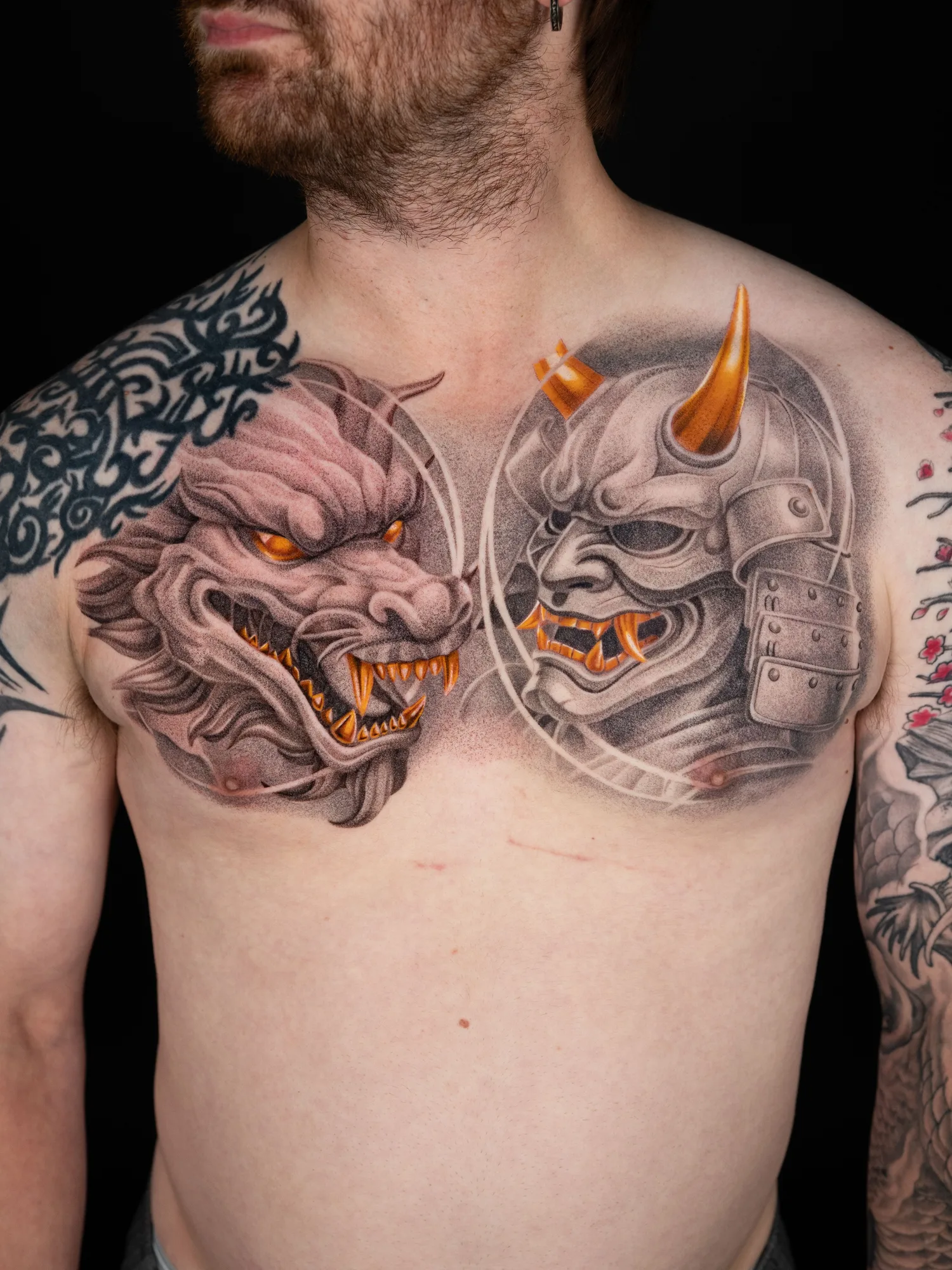 Chest tattoo featuring a dragon and samurai mask in detailed realism with gold accents