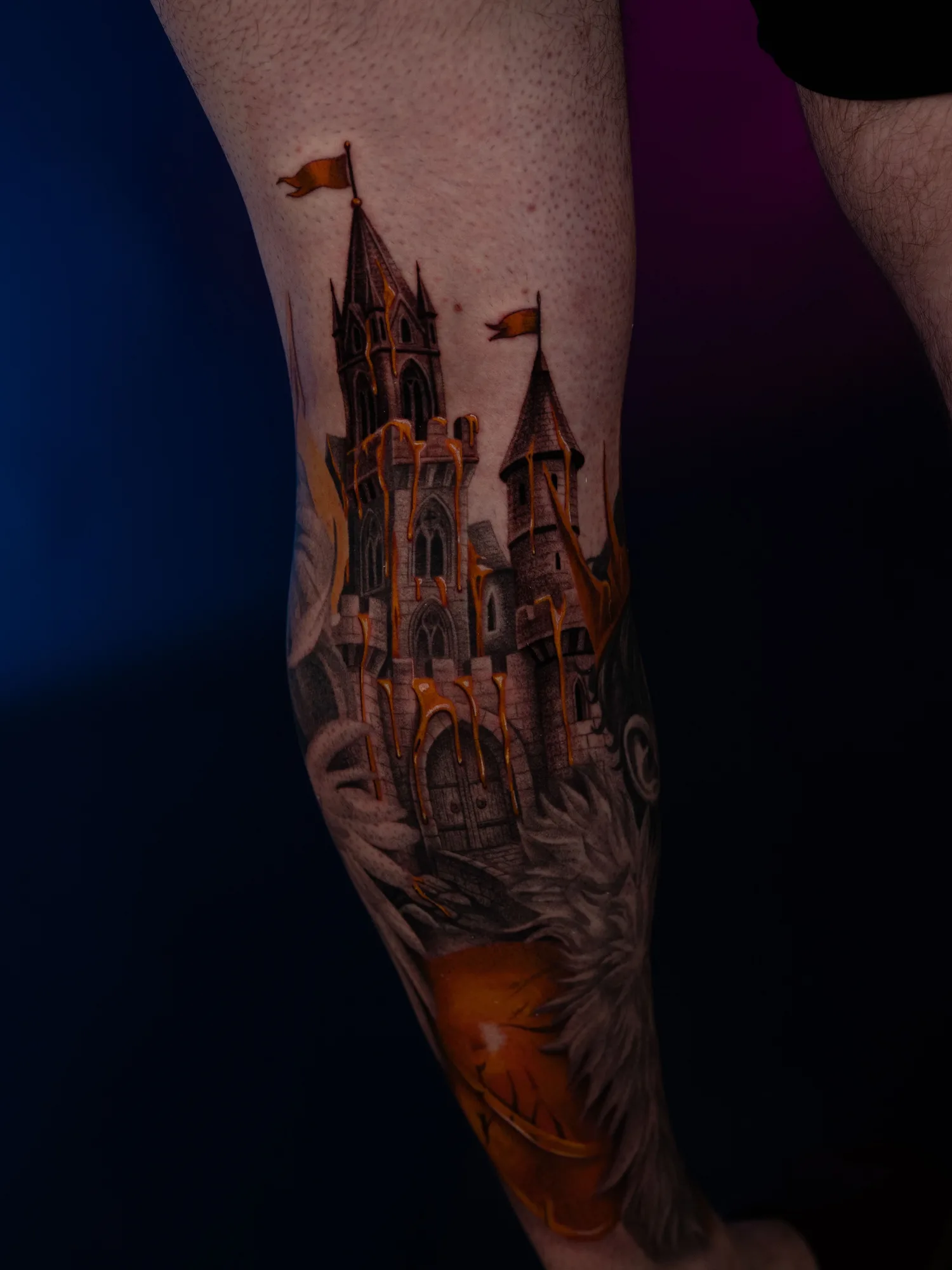 A detailed castle tattoo with gold accents on a leg.