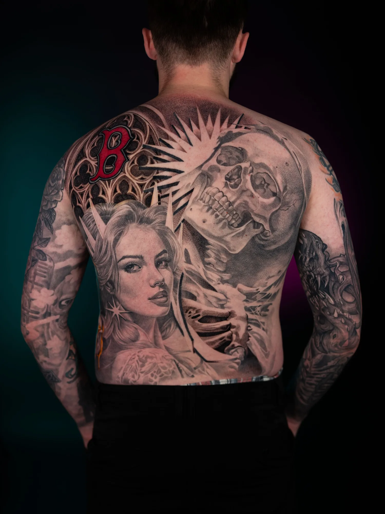 Tattoo of a woman's face and a skull on a man's back.