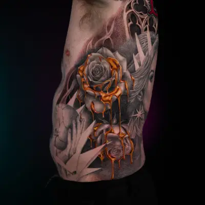 Tattoo of roses in black and grey on a rib cage with golden drips.