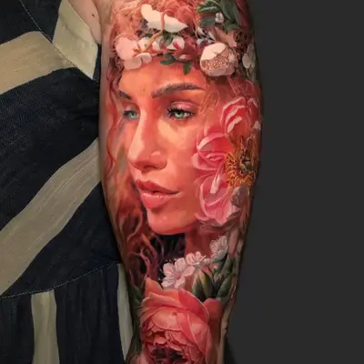 Tattoo of a woman's portrait with flowers on an arm sleeve.