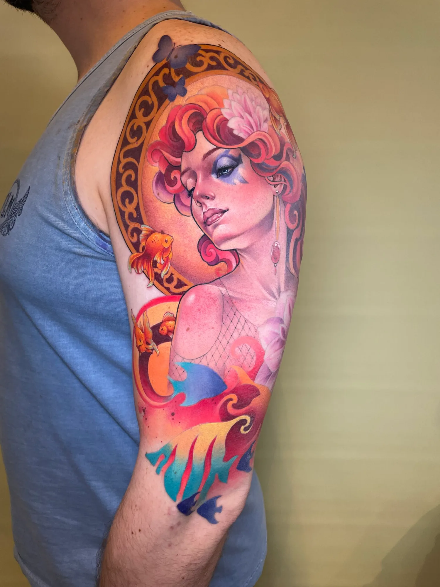Colorful tattoo of a woman with fish and floral elements.