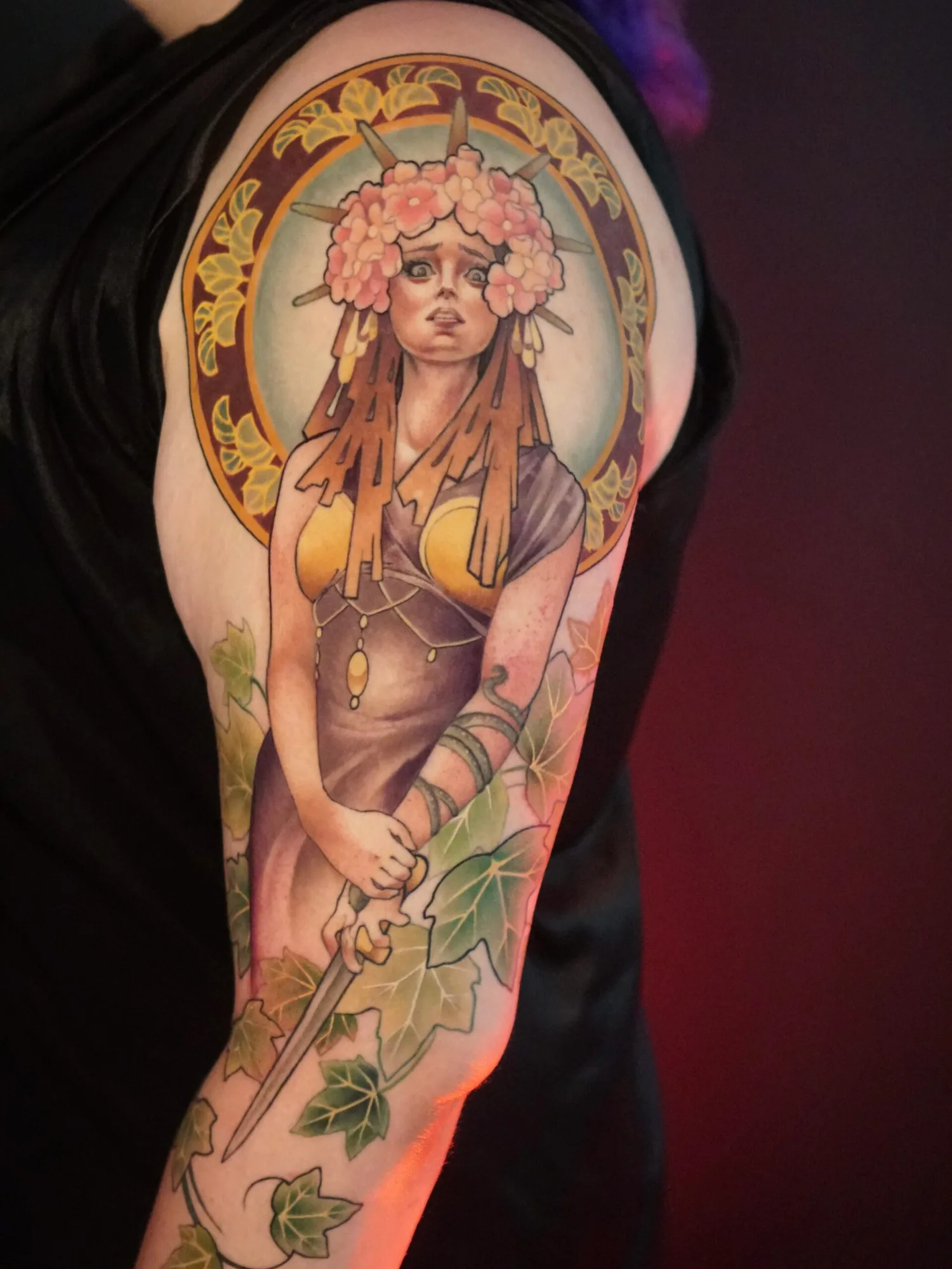 Colorful tattoo of a woman with floral headpiece and halo on arm.