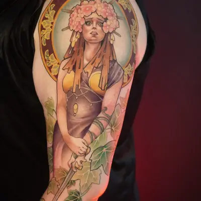 Colorful tattoo of a woman with floral headpiece and halo on arm.