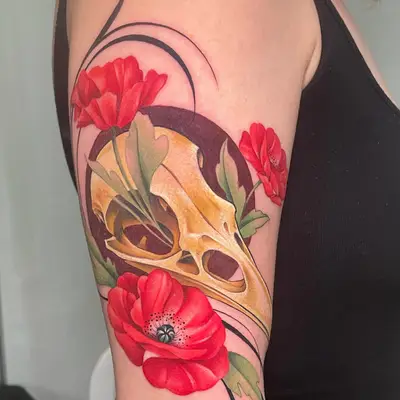 Tattoo of a skull with red poppies on upper arm.