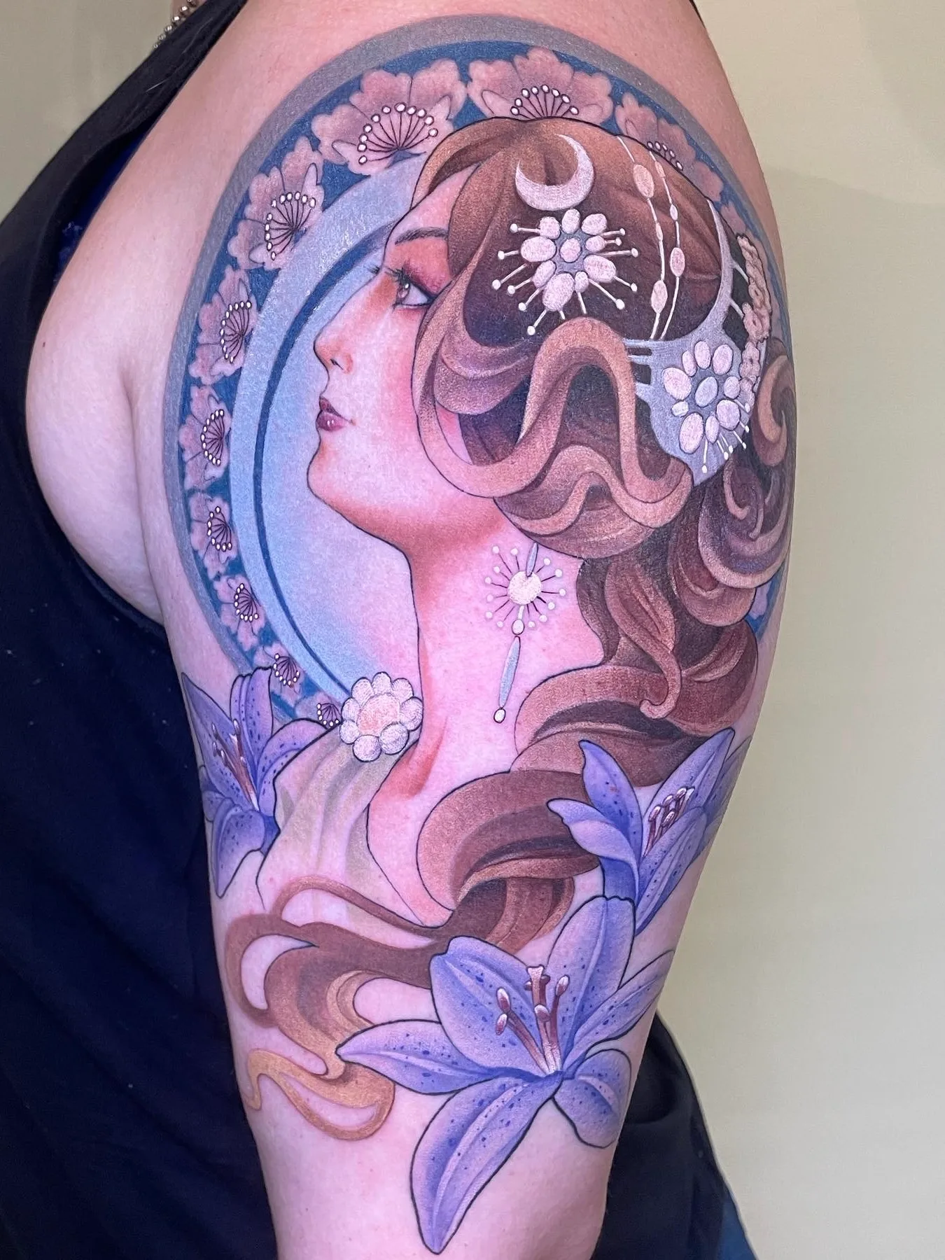 Tattoo of a woman's profile with flowers and crescent moon