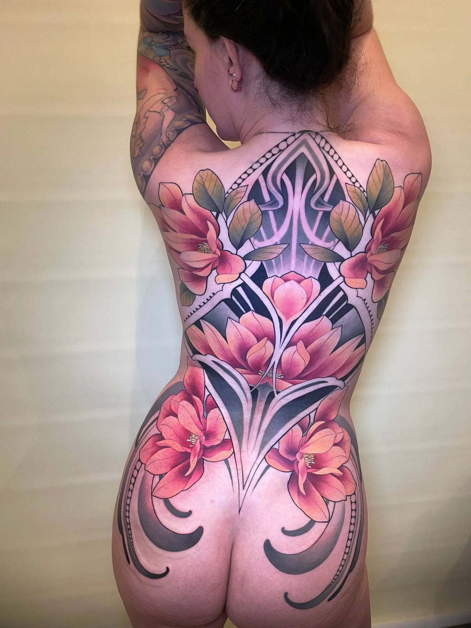 Floral and geometric back tattoo design on a person.