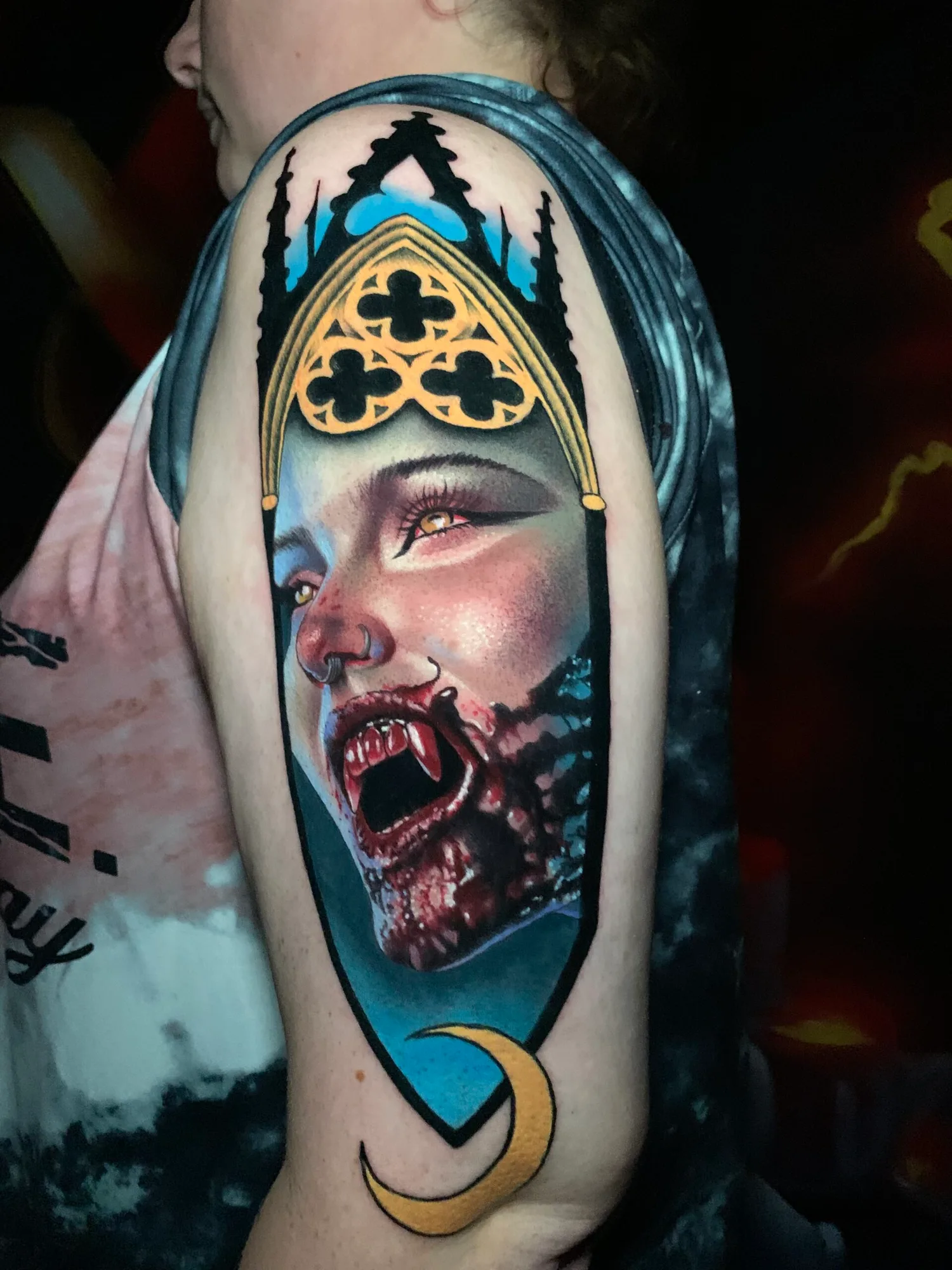 Vampire portrait tattoo with crown on upper arm.