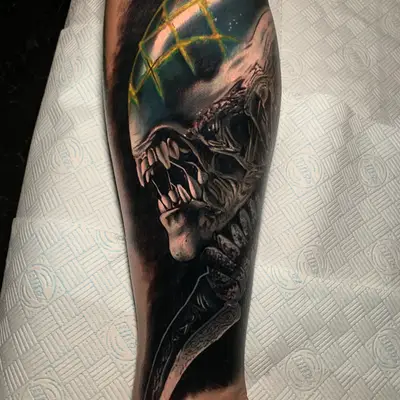 Tattoo of an alien creature with sharp teeth and a glowing dome on a leg.