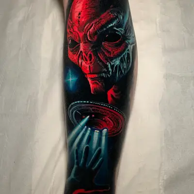 Tattoo depicting an alien face with a UFO and hand reaching towards light.