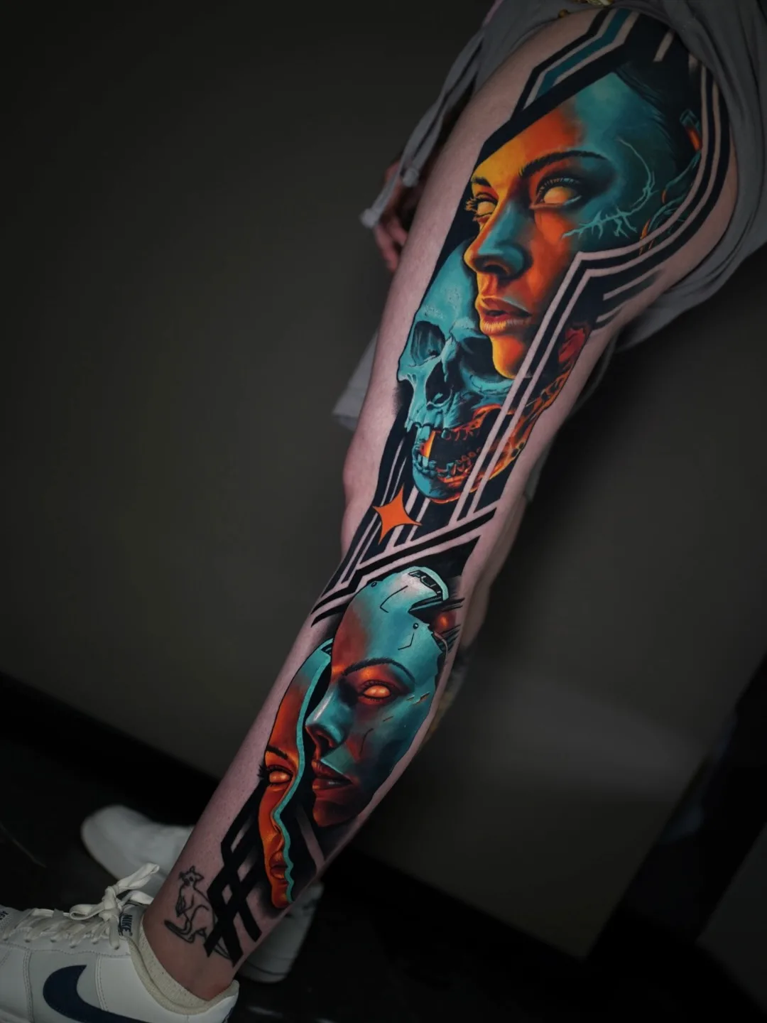 Abstract tattoo of faces and skull on leg