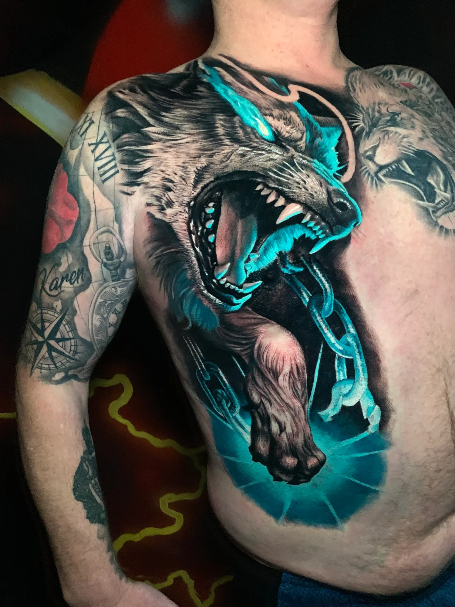 Tattoo of a fierce wolf with glowing blue accents on a person's chest.