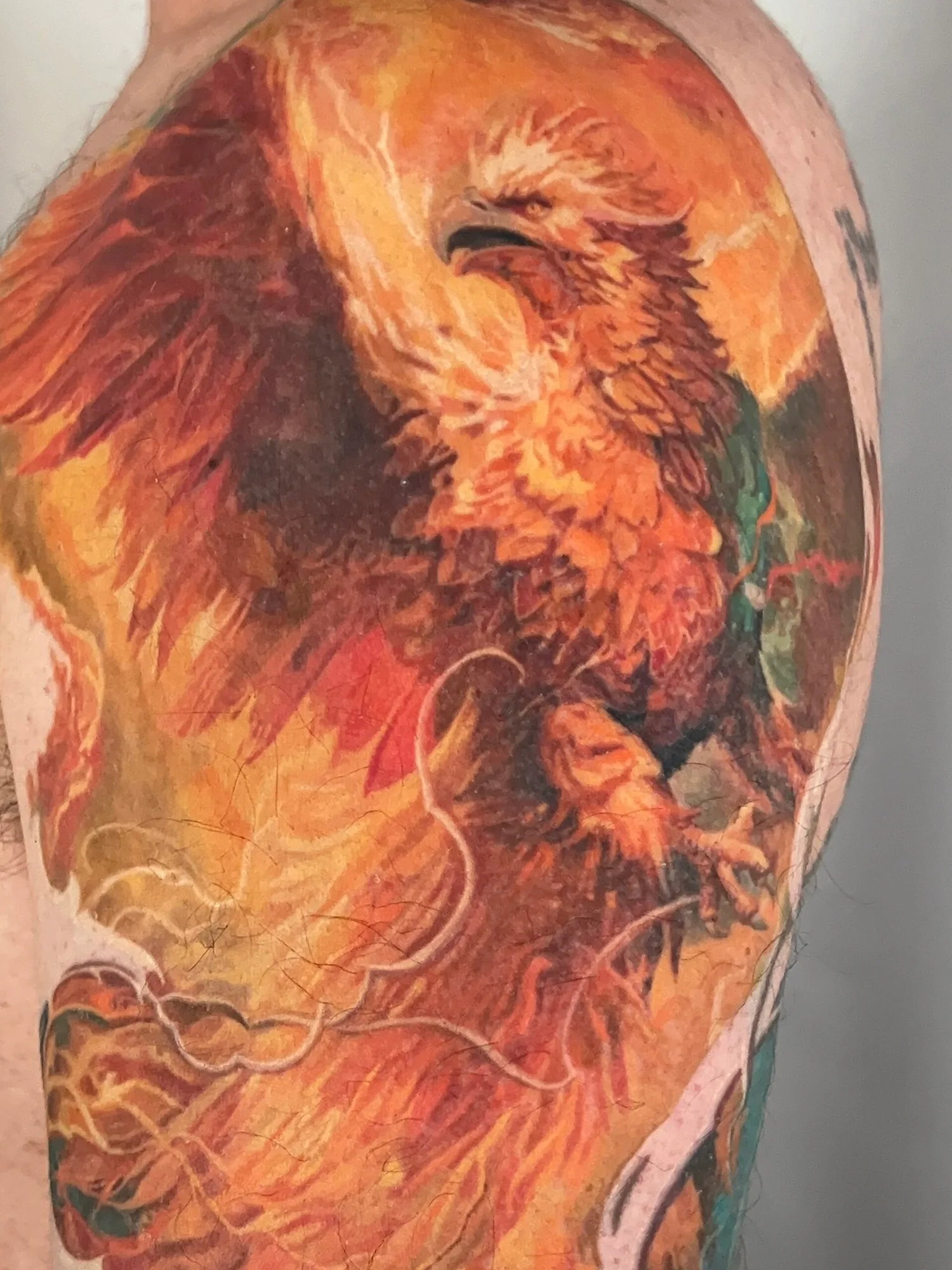 Vivid phoenix tattoo with flames on upper arm