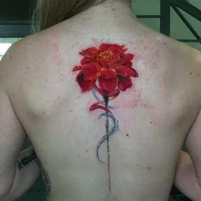 Colorful watercolor flower tattoo on woman's upper back