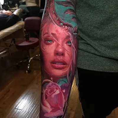 Forearm tattoo of a realistic woman's face with pink tones and a rose underneath.